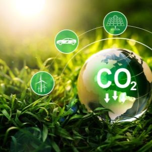 Globe showing CO₂ reduction surrounded by low-carbon icons, on grass with sunlight