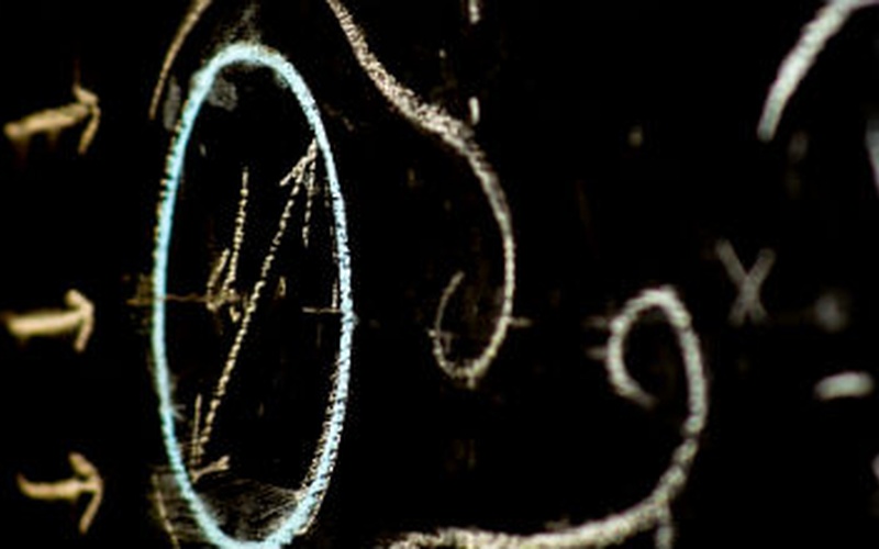 Close-up of chalk-drawn mathematical and fluid dynamics equations on a blackboard with curved arrow.
